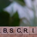 A wooden block spelling subscribe on a table