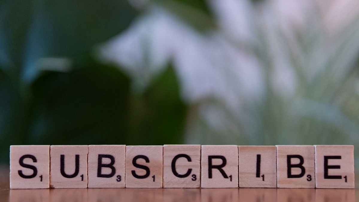 A wooden block spelling subscribe on a table