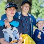 Mother with her two sons having fun outdoors, enjoying a sunny day.